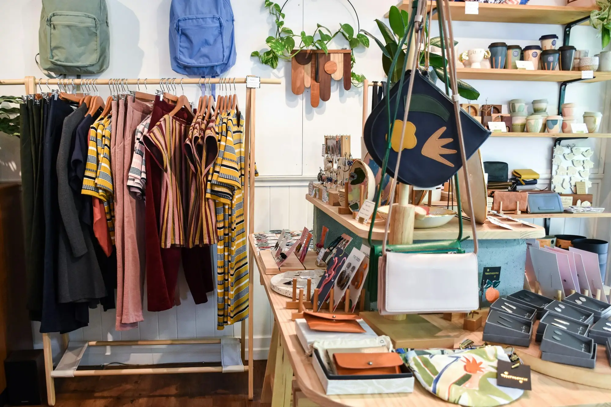 Newly stocked independent boutique with a rack of clothing, leather wallets and homewares on timber shelves, ready for opening day